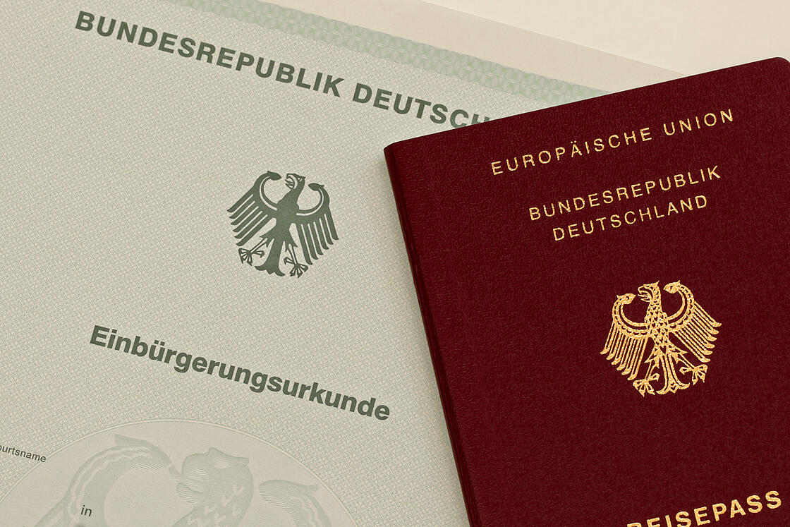 Nahaufnahme einer Einbürgerungsurkunde und eines Reisepasses der BRD