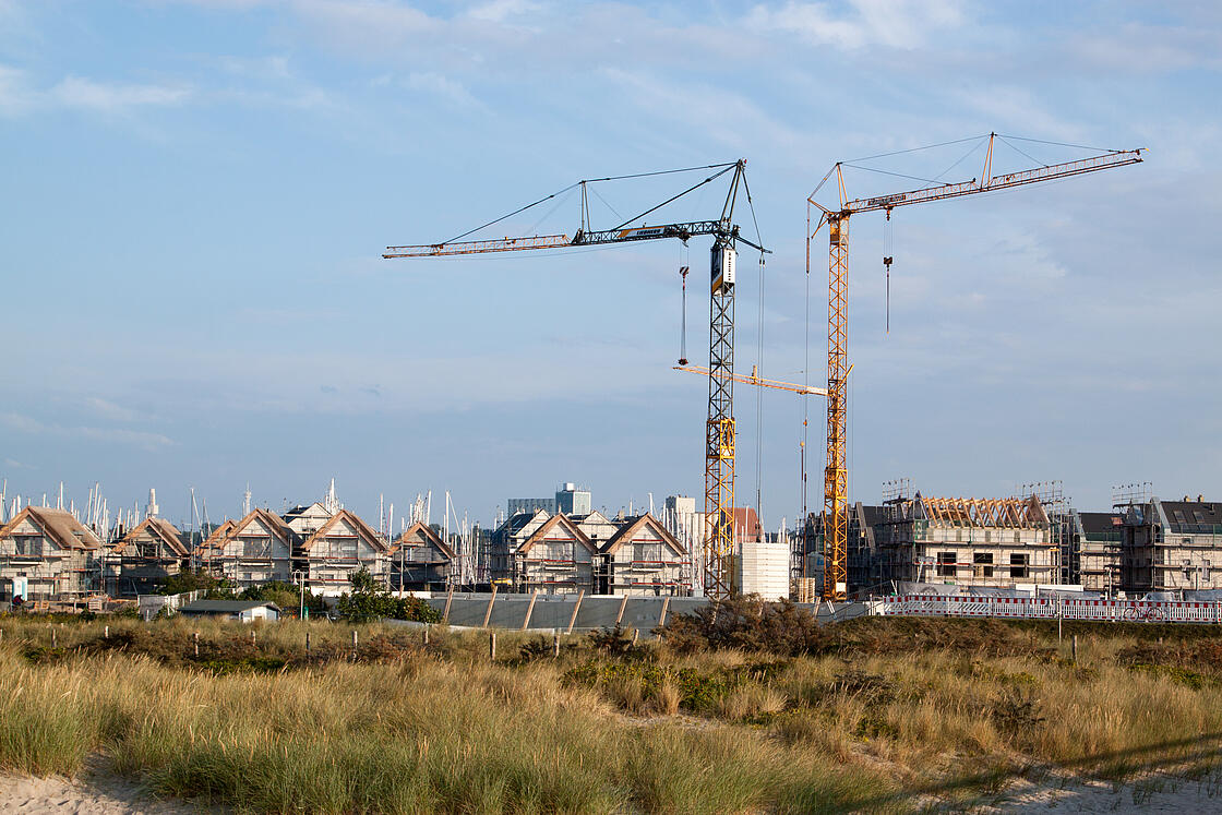 Baustelle an der Ostsee mit zwei großen Baukränen.
