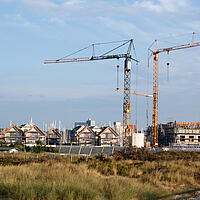 Baustelle an der Ostsee mit zwei großen Baukränen.