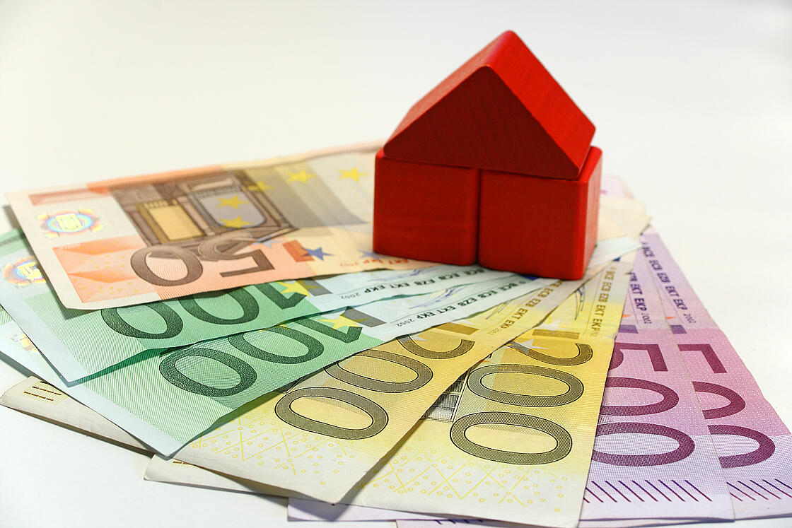 ein Haus aus Bauklötzen auf mehreren Euro-Geldscheinen