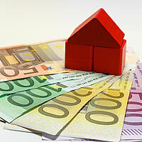 ein Haus aus Bauklötzen auf mehreren Euro-Geldscheinen