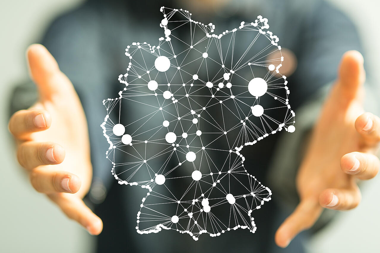 Zwei Hände, die eine stilisierte Landkarte von Deutschland umschließen, auf der digitale Netze dargestellt sind.