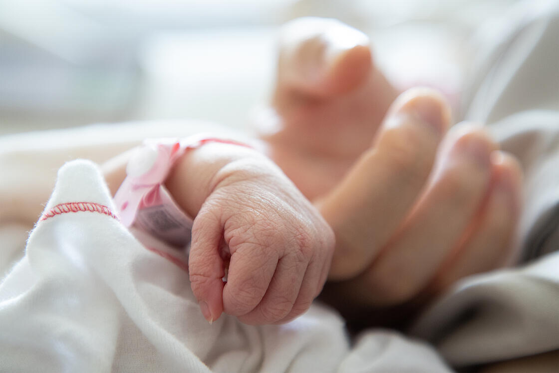 Neugeborendes das den Zeigefinger der Mutter hält