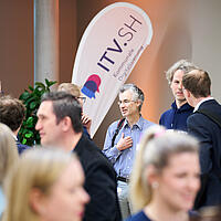 Teilnehmende des ITV.SH Forums im Foyer beim Austausch.