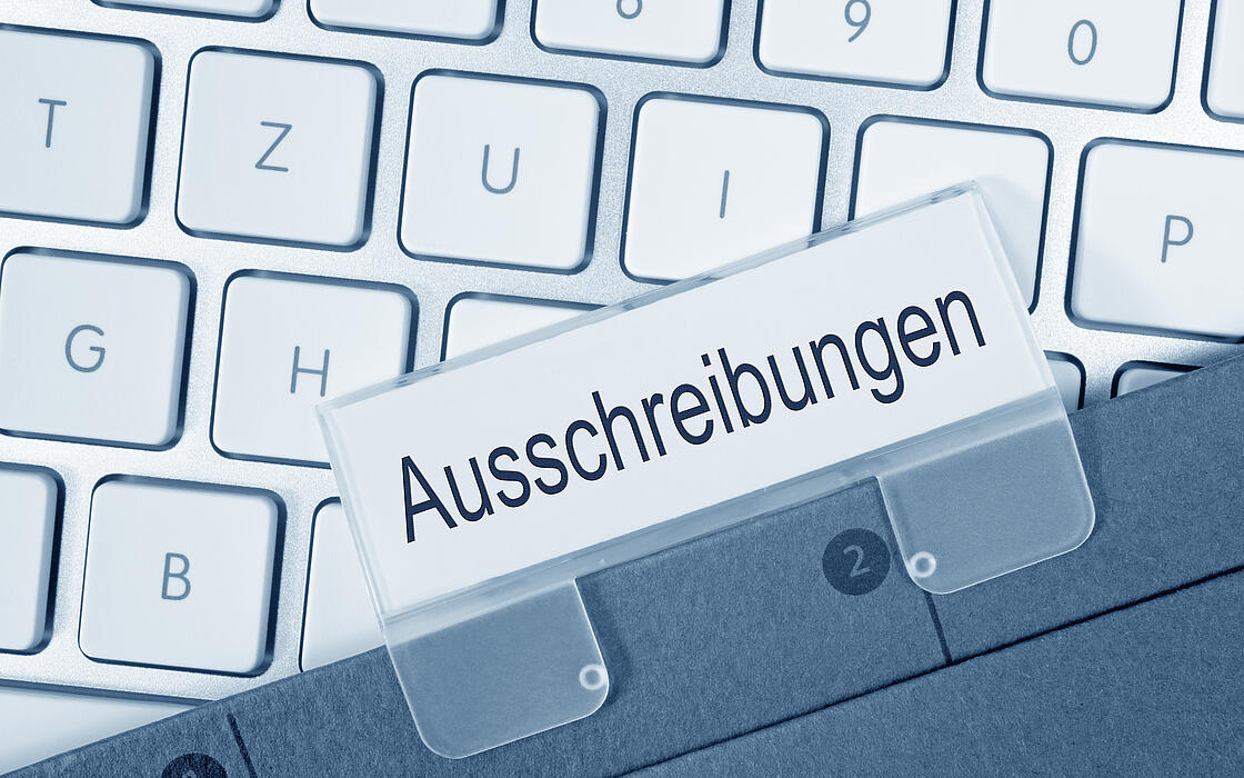 Nahaufnahme einer Aktentasche mit dem Schild Ausschreibung