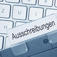 Nahaufnahme einer Aktentasche mit dem Schild Ausschreibung