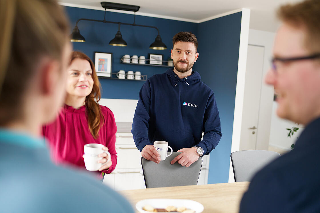 Vier Kolleg:innen in einer Kaffeeecke unterhalten sich