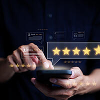 Ein Nutzer gibt über sein Handy eine Bewertung (fünf Sterne) ab.