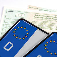 Nahaufnahme von zwei Autokennzeichen mit Zulassungsbescheinigung