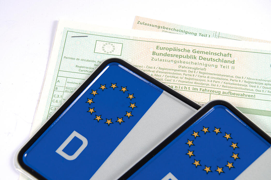 Nahaufnahme von zwei Autokennzeichen mit Zulassungsbescheinigung