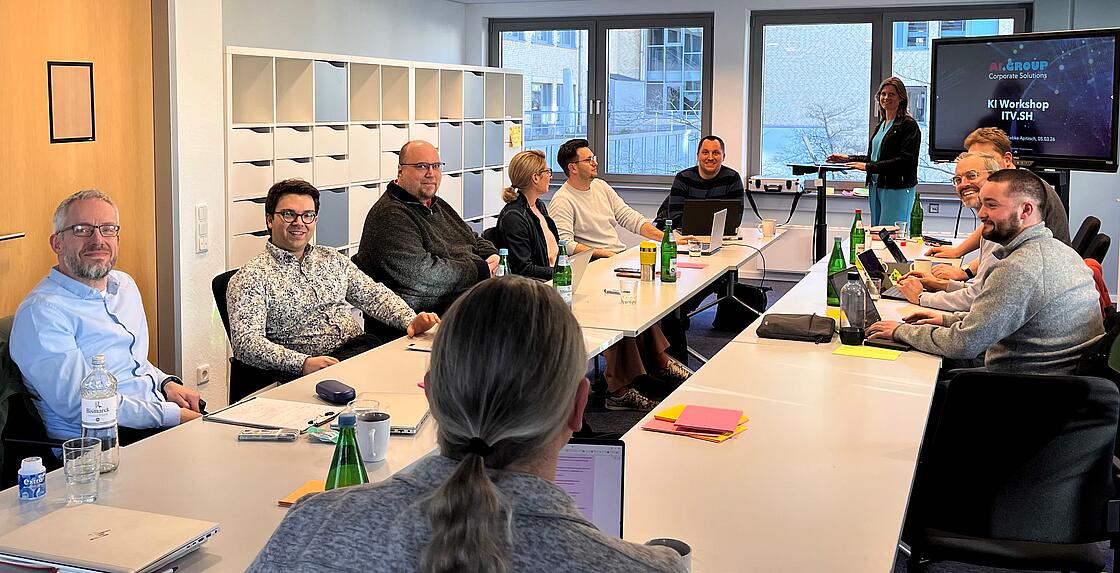 Teilnehmende des KI-Workshops sitzen an Tischen in einem Konferenzfraum.