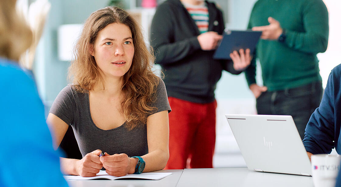 Besprechungssituation, in der eine Frau konzentriert im Gespräch ist.